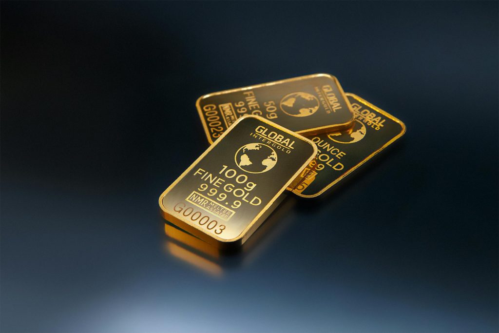 Drei Goldbarren mit 100 g, 50 g und 1 Unze, fotografiert auf dunklem Hintergrund Edel, schwer, vertraut – aber ist physisches Gold wirklich noch zeitgemäß, wenn Bitcoin überall dabei ist?